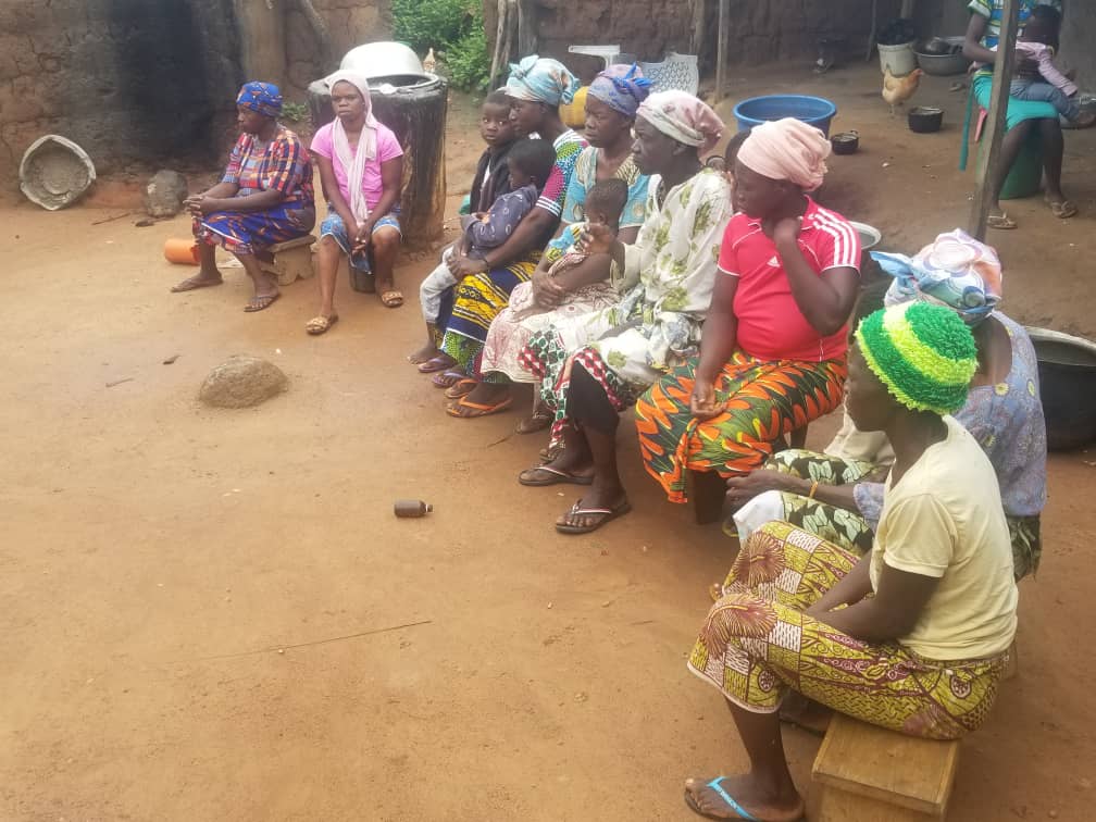 A row of villagers sit listening to Emmanuel teach