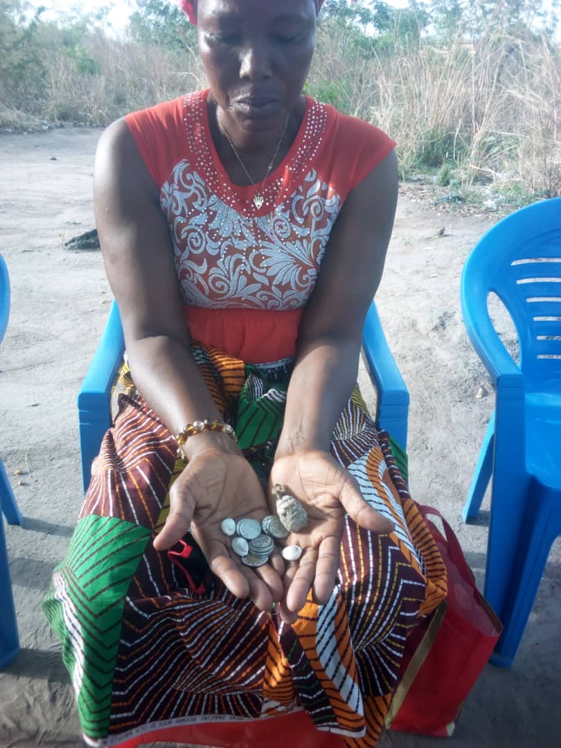 Mariama was brought from sorcery to salvation. She sits holding the charms and coins she received from the sorcerer before letting missionaries destroy them.